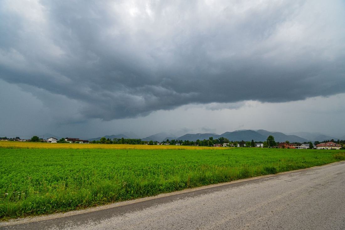 Ciemne chmury burzowe nad zielonym polem i drogą
